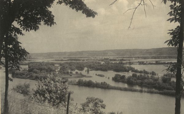 View from the bluffs in or near McGregor, Iowa. A fence and trees are in the foreground.