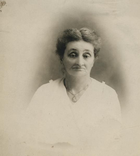 Studio portrait of Mrs. George Adams wearing white dress and large picture necklace. George Adams was the Sheriff of Jackson County.