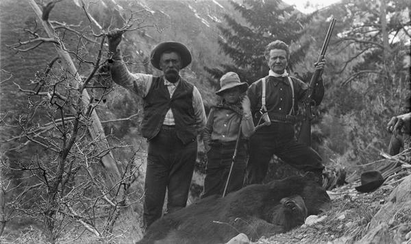 Senator Robert M. La Follette Sr., (with rifle), Robert M. La Follette Jr., and guide Jake Borah with the bear shot by the senator.