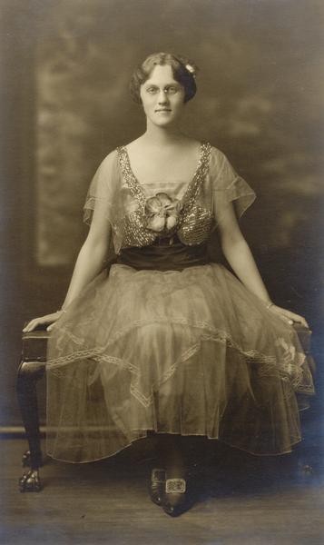 Studio portrait of Isabel Bacon La Follette, familiarly known as Isen, taken about one year before her graduation from the University of Wisconsin.  She married Philip La Follette, the son of Robert M. La Follette, Sr. Mrs. La Follette is wearing a tea dress and eyeglasses and seated on a bench.