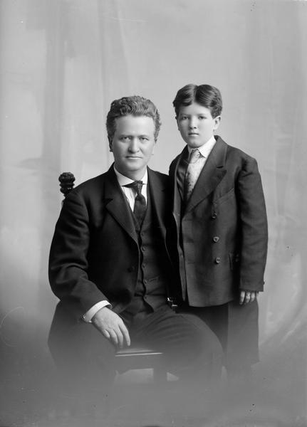 Formal seated portrait of Robert M. La Follette, Sr., with Robert M. La Follette, Jr. standing by his side. This portrait was taken in Madison at the end of the elder La Follette's first year in the U.S. Senate.