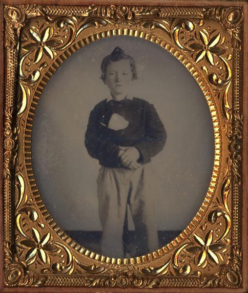 Quarter plate ferrotype/tintype portrait of Robert M. La Follette, Sr., at age 9 when he was attending the district school at Argyle, Wisconsin. Standing figure facing front, wearing jacket and pants. Hand-coloring on cheeks.