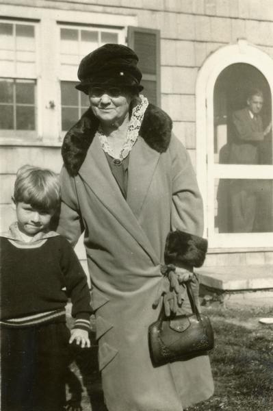 Snapshot of Belle Case La Follette with her grandson, Robert La Follette Sucher.  She is wearing a large hat and a coat with a fur collar and cuffs.  It is likely this family event coincided with the unveiling of the Robert M. La Follette, Sr., sculpture in the Capitol.