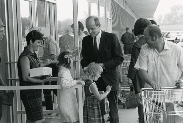 Senator William Proxmire hands his cards to constituents outside a Milwaukee grocery store.