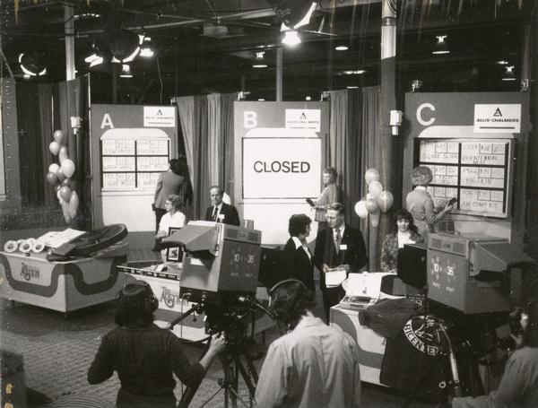 The set of the fundraising auction of Channel 10, Milwaukee's public television station. Senator William Proxmire is standing to the left of the closed B Board and Congressman Henry S. Reuss is standing to its right.