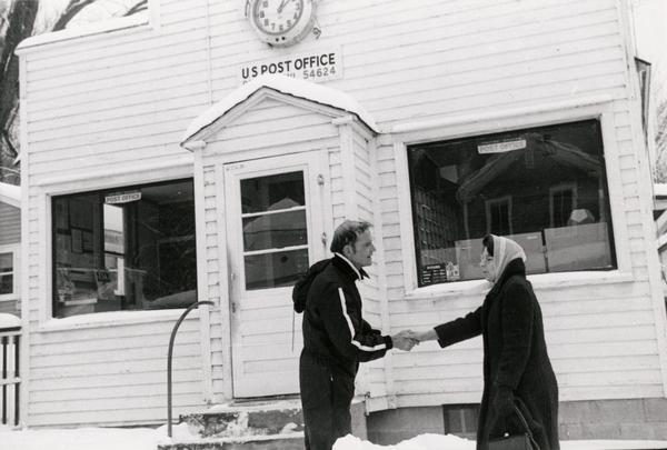 Senator William Proxmire walked thousands of miles in Wisconsin to meet constituents. Here he is, in a snowmobile suit, shaking hands with a woman outside the post office in De Soto.