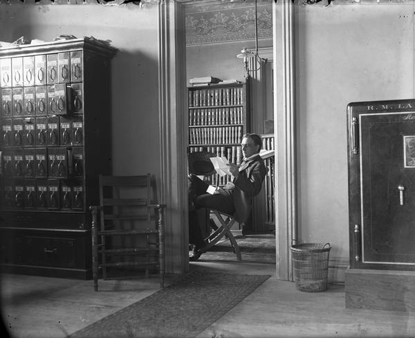 Gilbert Roe, Madison attorney and partner in the firm La Follette, Harper, Roe, seated in his office in the second floor of the Fairchild Block at 29 East Main Street.  In 1894 the partnership dissolved so that La Follette could better pursue his political career, but Roe, Zimmerman, and La Follette all moved to adjoining offices in the Fairchild Block.