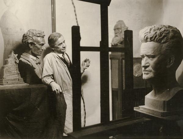 Sculptor Louis Mayer, with his larger-than-life portrait bust of Senator Robert M. La Follette, Sr., modeled in 1919.  Mayer was a Milwaukee-born painter and sculptor and a founder of the Society of Milwaukee Artists in 1912.  About 1912 Mayer relocated in New York where he devoted himself entirely to sculpture.  A bust of Abraham Lincoln is among the other representations of Mayer's work seen in the photograph.