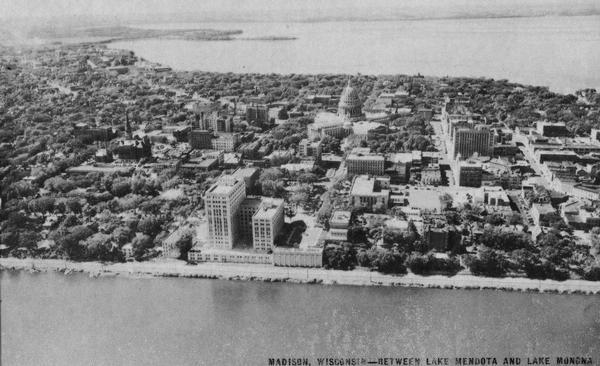Aerial view of the Madison isthmus looking north. Caption reads: "Madison Wisconsin — Between Lake Mendota and Lake Monona".