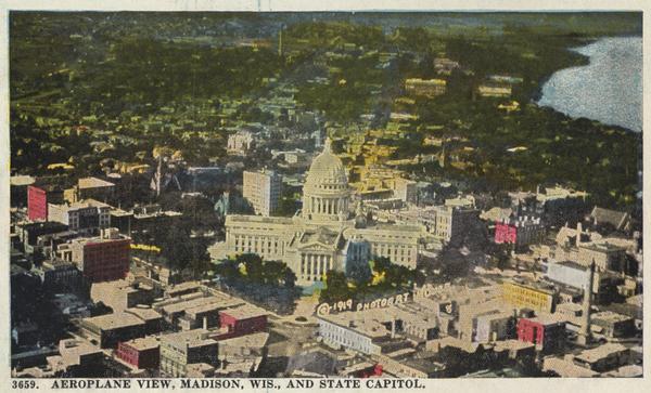 Colorized aerial view of isthmus looking northwest over the Wisconsin State Capitol. Caption reads: "Aeroplane View, Madison, Wis., and State Capitol."
