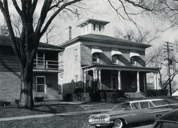 The James Bowen House at 302 South Mills Street. There is a station wagon parked in front of the building.