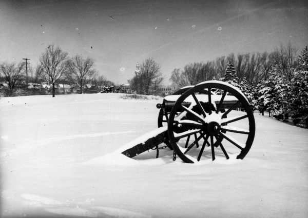 Winter scene with a Civil War cannon partially covered with snow at Camp Randall.