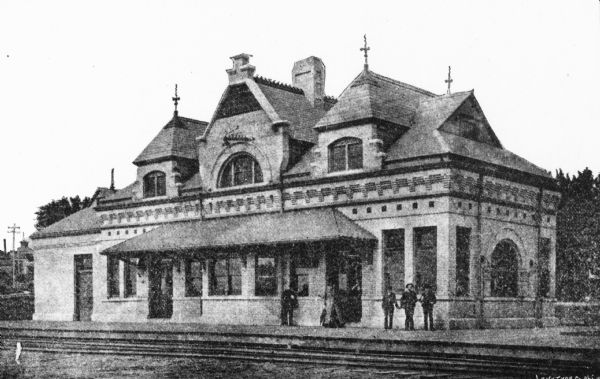 Chicago, Milwaukee & St. Paul passenger depot with several people standing in front of the building. This is the Franklin Street station on East Wilson Street designed by Edward Townsend Mix.