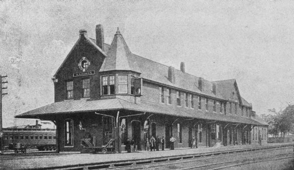 Original Chicago & North Western Railroad passenger station, 219 South Blair Street at East Wilson Street, with a few men gathered out front.  Torn down in 1910.