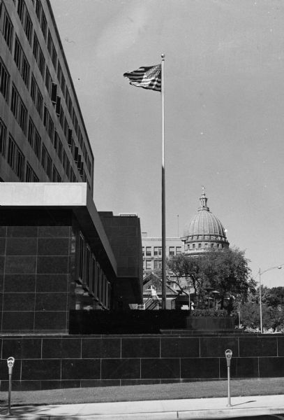 An American flag at the main entrance to the City County Building with the Wisconsin State Capitol building in the background.