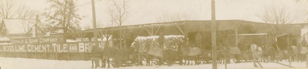 People pose outside of Conklin & Sons store. According to the sign,  they sold wood, lime, cement, tile, and brick.