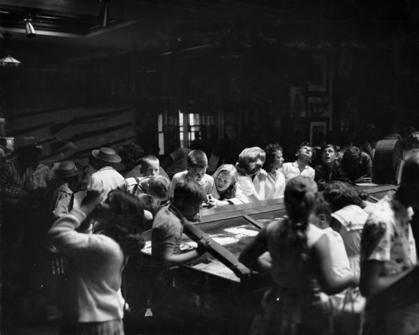 Children and adults gather around a showcase in the G.A.R. (Grand Army of the Republic) Memorial Hall on the top floor of the Wisconsin State Capitol.