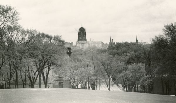 View in winter from Bascom Hill on the University of Wisconsin-Madison campus of the Wisconsin State Capitol (the fourth State Capitol, the third in Madison), during the construction of the dome.  The earlier Capitol can still be seen standing next to the new building.