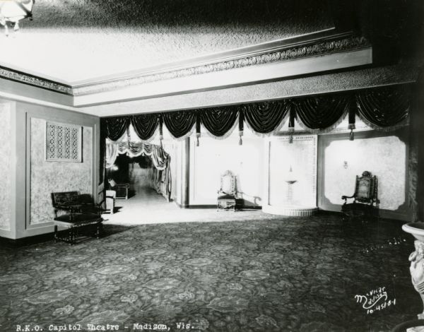 Capitol Theatre Mezzanine with chairs against the walls, and a fountain in the foreground on the right.