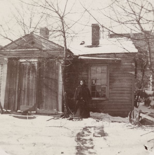 The James Duane Doty residence on Doty Street (formerly Clymer Street), the first "Executive Mansion" in Madison, occupied in 1841-1844 by the Territorial Governor. Jane Williams is standing by the door; she was a sister of "Prof." Williams, an African American barber, who had at one time been valet to Edwin Forrest, the actor.