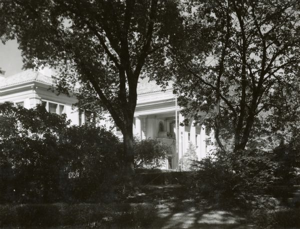 Detail of the Executive Mansion through garden shrubbery. The residence is located at 99 Cambridge Road in Maple Bluff.