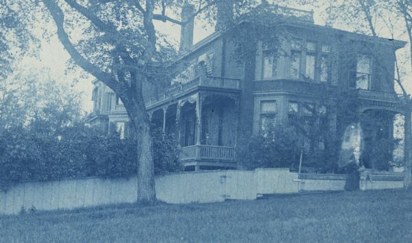 Cyanotype of the Fairchild Residence, home of Lucius Fairchild. A woman is standing on the lawn.