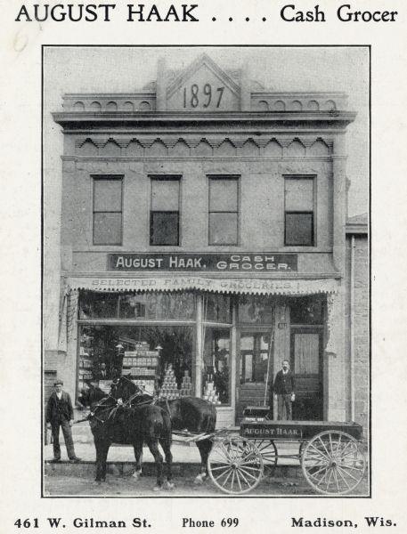 The storefront of August Haak, cash grocer, at 461 West Gilman Street. Two men are posing in front of the store. Caption reads: "August Haak . . . . Cash Brocer" and "461 W. Gilman St. Phone 699 Madison, Wis." The awning has a sign that reads: "Selected Family Groeries."