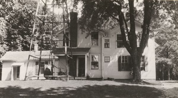 The J.C. Hawley house, also known as the Evergreens. The base of a water tower is in the front yard on the left.