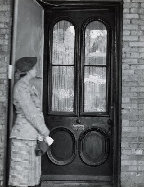 The front door of the Herfurth house, 703 East Gorham Street, built by Theodore Herfurth around 1870 and owned in 1952 by Mrs. Ralph Dennis. A woman is standing near the door on the left.