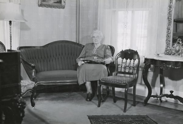 The front parlor of the Herfurth house, 703 East Gorham Street, with Mrs. Caleb Harrison (born Lucy Herfurth) sitting on a sofa. The house was built by Theodore Herfurth around 1870 and was owned in 1952 by Mrs. Ralph Dennis.