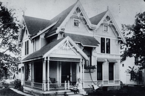 Exterior of a house at 1030 Jenifer Street, built in 1883-84 with a family sitting on the front porch.