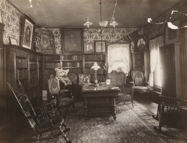 Interior of the Keyes residence, home of political leader Elisha W. Keyes.  According to Keyes' daughter, Mrs. John C. Gaveney of Whitehall, Wisconsin, the framed pictures above the book case are, from left to right: Lincoln, Wisconsin State seal from the Wisconsin State building at the World's Columbian Exposition, Chicago, 1893, Theodore Roosevelt, unknown, McKinley, and unidentified.