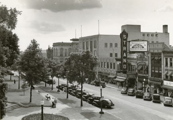 Elevated view of East Mifflin Street on the Capitol Square. The Strand Theater is on the right. Automobiles are parked at an angle on both sides of the street.