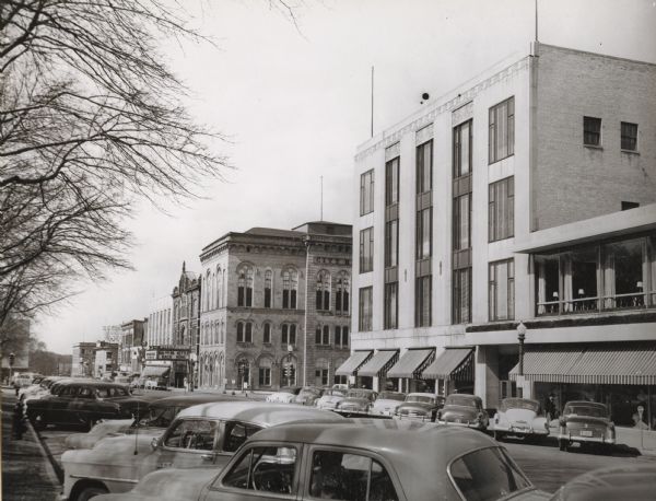 View looking west down Mifflin Street showing the old City Hall, the Parkway Theater, and Manchesters Department Store. Automobiles are parked at an angle on both sides of the street.