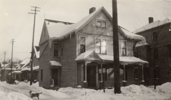 Mills Street House, 211 North Mills Street. Snow is on the ground, and a dog is standing on the left.