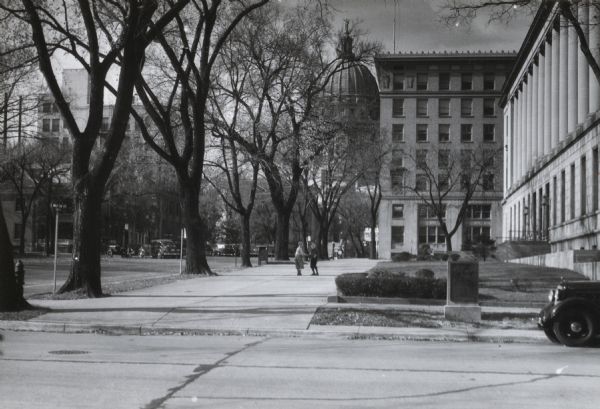 Post Office and insurance buildings (on right), at Monona Avenue and East Wilson Street. The Wisconsin State Capitol is in the background. Two children are playing on the sidewalk.