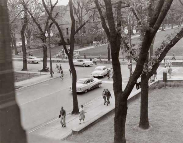 An elevated view of the intersection of Park and State Streets from the Wisconsin Historical Society. Bascom Hill can be seen in the right background, and in the left background can be seen what today is known as Music Hall.