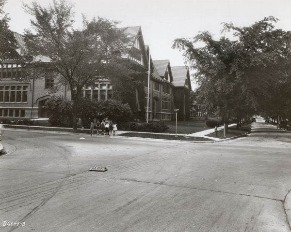 View from across the street of the Randall School on Regent Street. Special street signs on the road are visible. A group of students appear to be waiting to cross Regent Street. 1802 Regent Street at 10 N. Spooner Street.