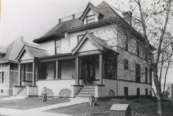 View of the Fritz and Robert Lamp house at 1024 Sherman Avenue that was built in 1897. A young child and a dog are in the front yard.