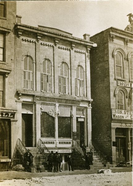 View of the State Bank located at 7-9 South Pinckney Street, near the intersection of East Washington Avenue. A group of men are posing in front.