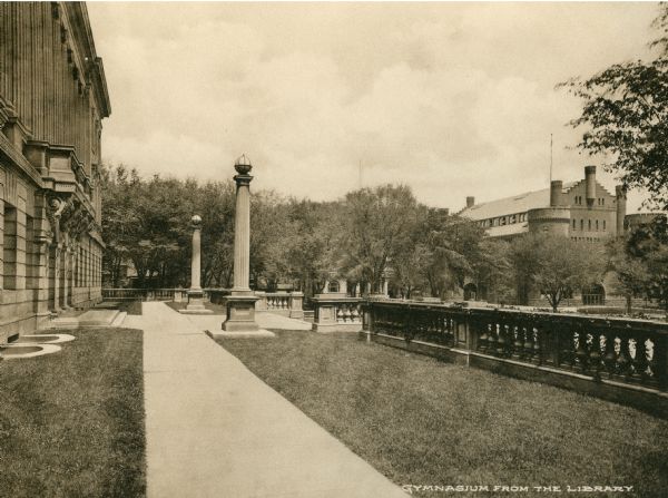 View of the State Historical Society of Wisconsin terrace, looking toward the Memorial Union and Armory (Red Gym or Old Red). Caption reads: "Gymnasium from the Library."