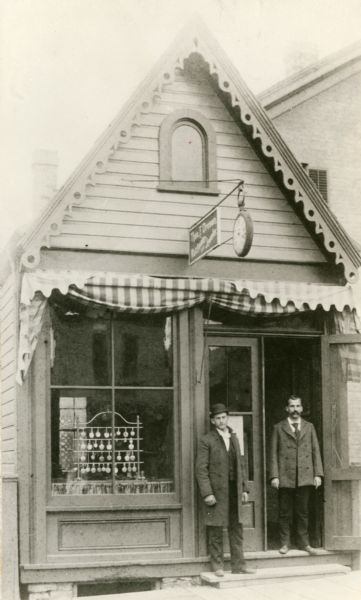 Storefront view of the Theodore F. Dresen jewelry store at 216 State Street. Two employees, one possibly being Theodore Dresen, are standing at the doorway in front of the storefront.