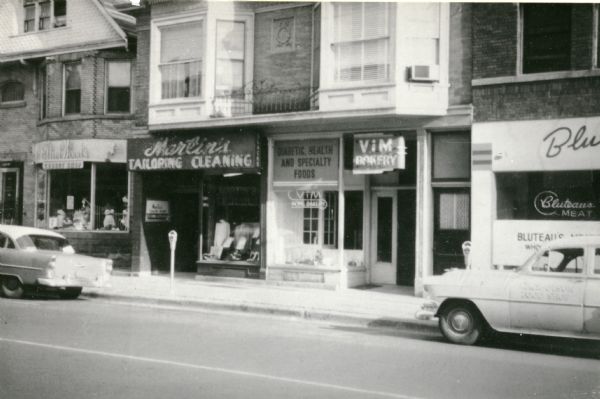 View of Martin's Tailor Shop and Cleaners at 419 State Street, owned by Martin Deutschkron. The following businesses are, (at left): Ethel Wood's Corset Shop, 417 State Street; (at right): Vim Whole Grain Baking Center, 419 State Street, and Bluteau's Meat Market, 421 State Street.