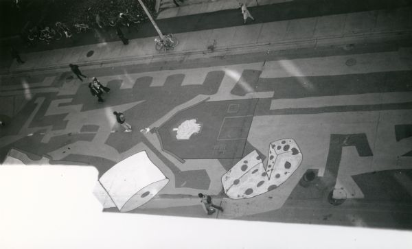 A view looking down from the Wisconsin State Historical Society building to artwork on the cement of State Street Mall. These paintings on the 800 and 900 blocks of State Street were created by the University of Wisconsin's Art Department Association of Undergraduate Artists. Using several different colors, the artists used paint that was donated by Mautz Paint Company of Madison.