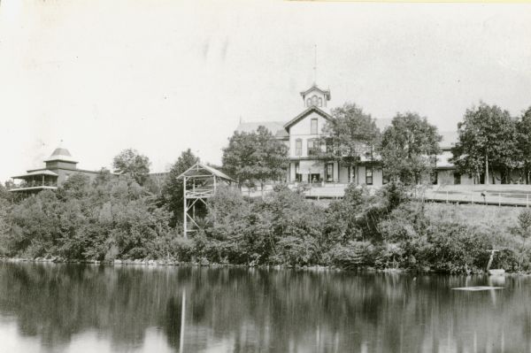 View across water towards the Tonyawatha Spring Hotel on Lake Monona. The hotel, on the east shore of the lake, is located in Blooming Grove Township, just outside of Madison. On July 31, 1895, the hotel was destroyed by a fire.