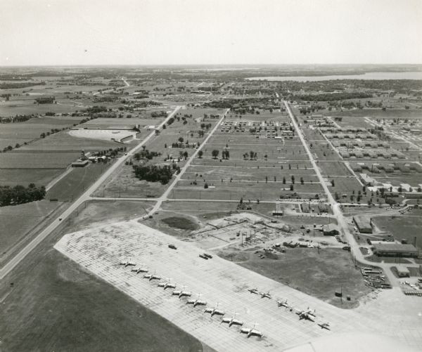 An aerial view of Truax Field, now also called Dane County Regional Airport. In addition to commercial flights, Truax Field is also home to the Army National Guard and the Wisconsin Air National Guard. A line of National Guard airplanes are visible.