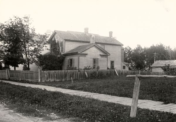 View of a home on University Avenue, with a fenced-in yard and several trees.
