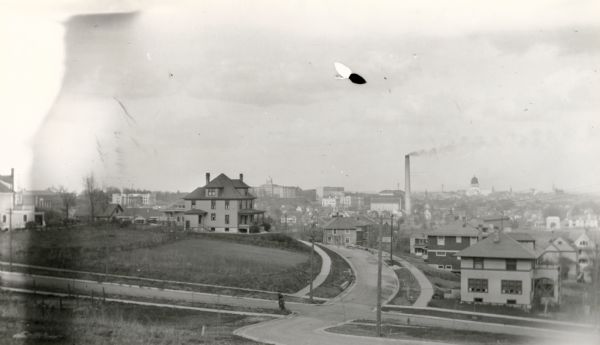 Elevated view of University Heights, looking north from Ely Place towards Bascom Hall. The following houses are visible: Professor Richard T. Ely house, 205 N. Prospect, Professor Victor Lenher house, 1718 Summit Avenue built in 1906, Professor Wayland J. Chase house, 1727 Summit Avenue built in 1907, Lewis Albert Anderson house, 1708 Summit Avenue built 1912, and Professor Edward Farrington house, 208 Lathrop Street built 1913. In the distance is Bascom Hall in the center, and on the right is the Wisconsin State Capitol.