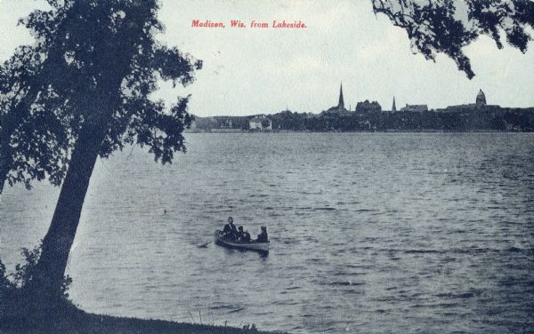 View from shoreline looking towards the city of Madison from across Lake Monona. Several people are in a rowboat on the lake. Caption reads: "Madison, Wis. from Lakeside."