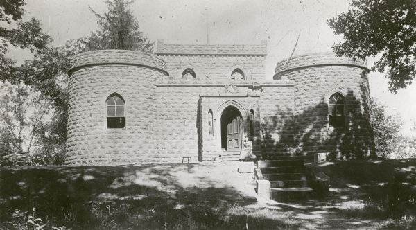 Benjamin Walker Castle, 1862-1893 in the 900 block East Gorham Street. The front door is partially open, and a woman is sitting to the right of the entrance.